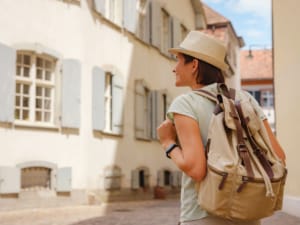 Tourisme - Femme avec sac à dos visitant une ville touristique